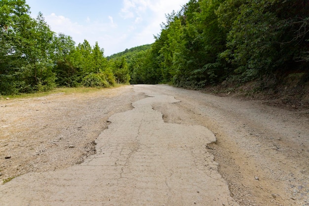 Po trzęsieniu ziemi i silnej burzy pozostałości asfaltowej drogi w górach. Zamknięta droga. Zniszczona droga asfaltowa. Połamany asfalt, pęknięcia i osuwiska. Zdjęcie wysokiej jakości