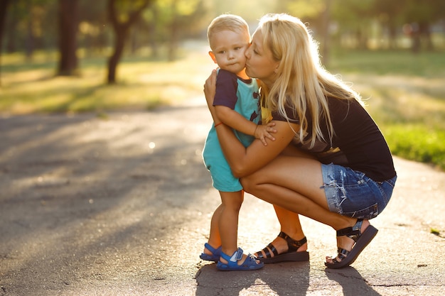 Pocałunek i uściski mamy i syna. Mama i syn chodzą w parku lato.