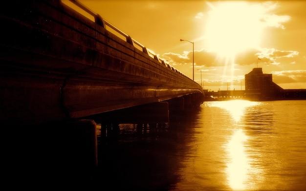 Pociąg przechodzi przez most, a słońce świeci na wodzie.