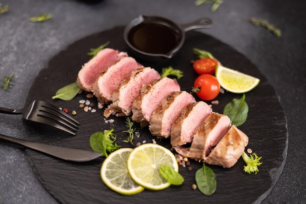 Pocięty na grillu gotowany kawałek filetu tuńczyka na czarnej kamiennej desce do serwowania