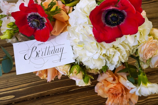 Zdjęcie pocztówka internetowy baner z pozdrowieniem urodzinowym z napisem szczęśliwy urodzin bukiet kwiatów z notatką z gratulacjami