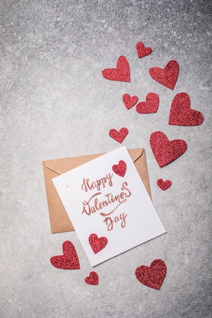 Pocztówka Walentynki. Happy Valentine's day napis i czerwone serca na vintage betonowym szarym tle