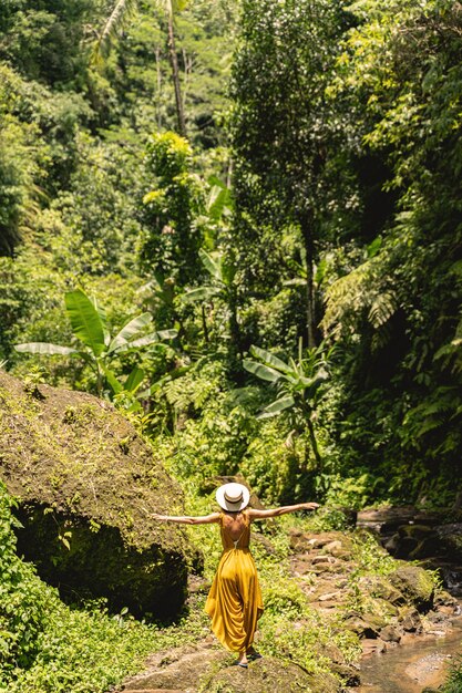 Poczucie wolności. Szczupła kobieta stojąca twarzą do dżungli podczas kręcenia swojego bloga podróżniczego