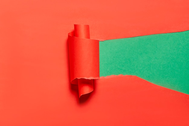 Podarty i zwinięty kawałek czerwonego papieru na zielonym tle kopiuje przestrzeń jasne i kreatywne tło