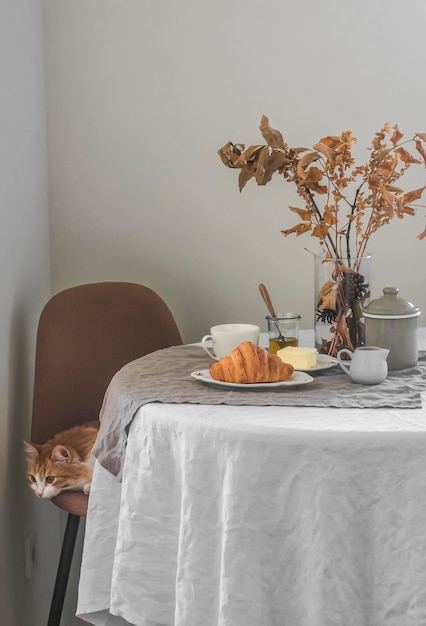 Podawany na śniadanie croissant kawa maślany miód w przytulnej kuchni