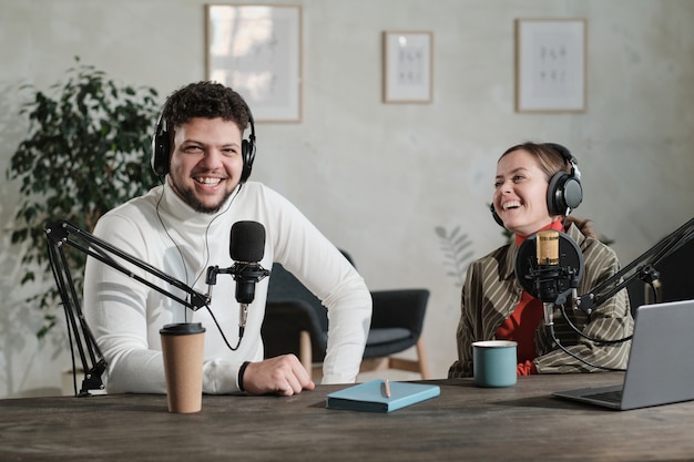 Podcaster rozmawiający z mikrofonem nagrywa podcast w studio ze swoim kolegą