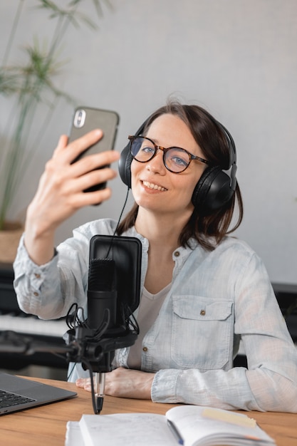Podcaster tworzy treści europejska kobieta nagrywa podcast z mikrofonem i słuchawkami kaukaskimi