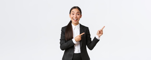 Podekscytowana kobieta azjatycki menedżer sprzedawczyni lub agent nieruchomości pokazujący dom na sprzedaż wskazującymi palcami prawy przedsiębiorca wprowadza projekt lub wykres na spotkaniu biznesowym, stojąc w kolorze białym tle