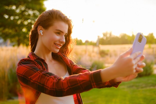 Podekscytowana młoda dziewczyna robi sobie selfie, stojąc na polu.