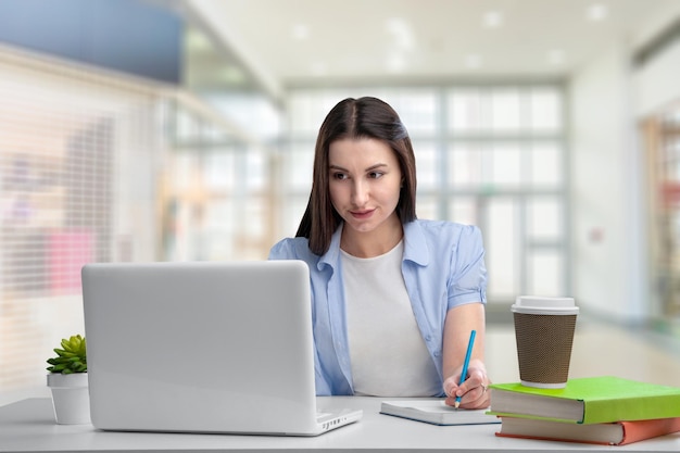 Podekscytowana młoda kobieta siedzi przy biurku z laptopem