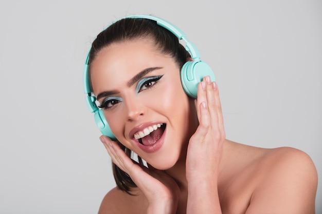 Podekscytowana młoda kobieta słucha muzyki w słuchawkach tańcząca dziewczyna słuchająca muzyki za pomocą bezprzewodowego zestawu słuchawkowego