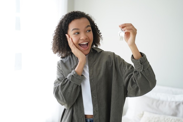 Podekscytowana, szczęśliwa lokatorka rasy mieszanej pokazuje klucze do nowego domu Reklama usługi wynajmu nieruchomości