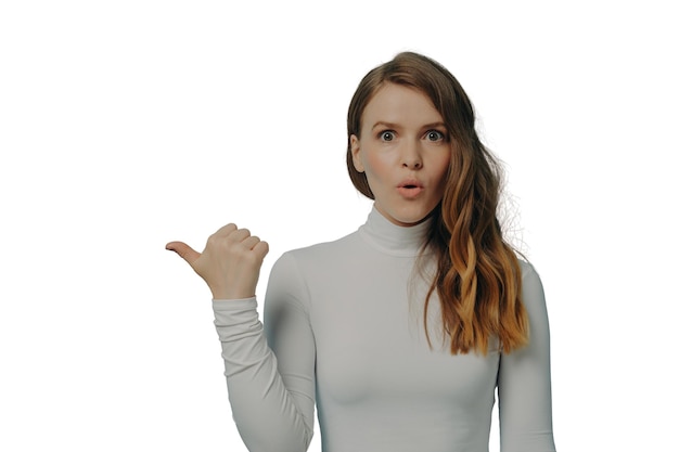 Podekscytowana tysiącletnia dama stojąca z palcem wskazującym kciuk na miejsce na kopię produktu reklamowego