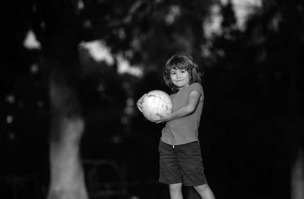 Podekscytowane dziecko chłopiec kopie piłkę w trawie na zewnątrz piłka nożna dzieci dzieci grają w piłkę nożną aktywna piłka