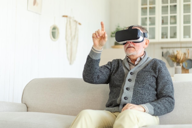 Podekscytowany dojrzały starszy mężczyzna noszący zestaw słuchawkowy z okularami wirtualnej rzeczywistości metaverse vr w domu dziadka