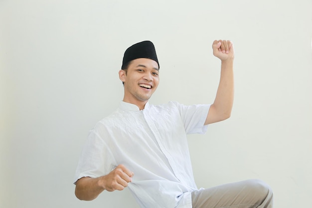 Podekscytowany młody azjatycki muzułmanin podnoszący pięści i świętujący zwycięstwo w Ramadanie