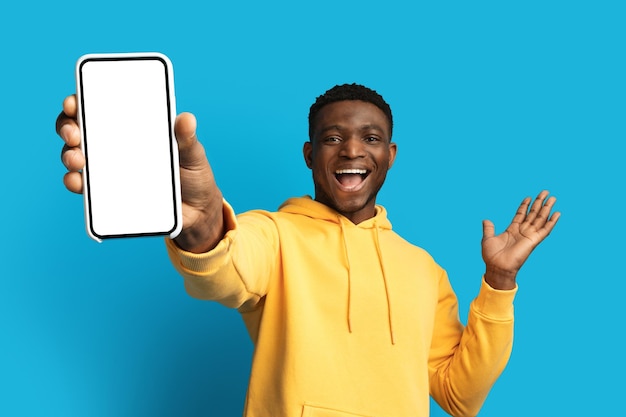 Podekscytowany młody czarny facet pokazujący duży telefon z pustym ekranem