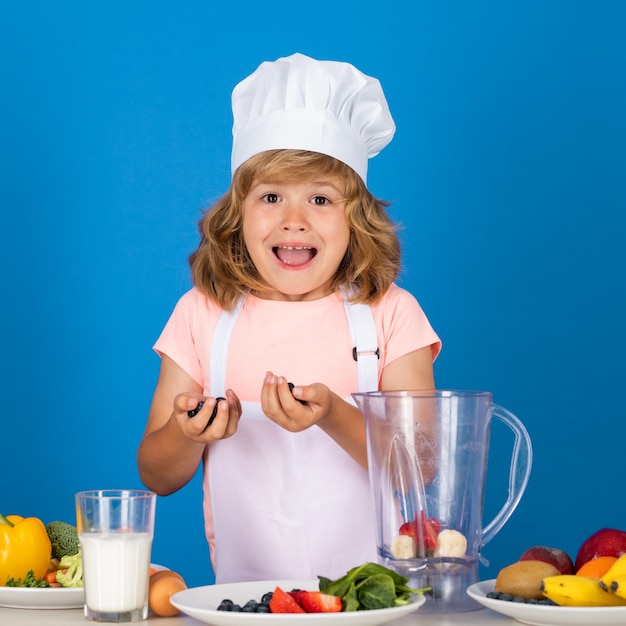 Podekscytowany zabawny kucharz kucharz portret szefa kuchni dziecko w kapeluszu kucharza gotowanie w domu dziecko chłopiec przygotowuje jedzenie fr