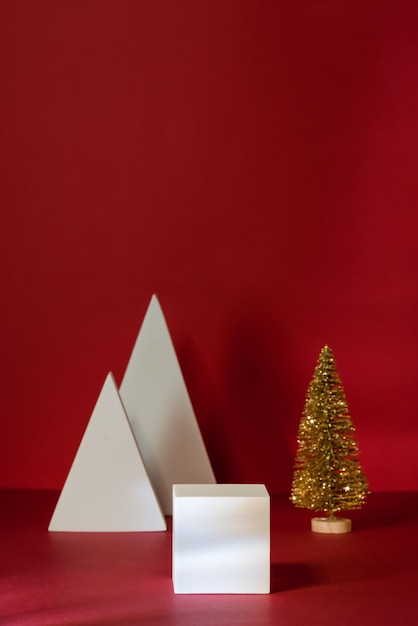 Podium lub cokoły i złota mała choinka do wyświetlania produktów świątecznych na czerwonym tle