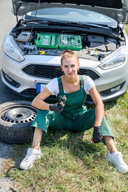 Podkreślił, młoda kobieta, patrząc na silnik swojego samochodu. Problemy z podróżą. Samochód wymaga naprawy.