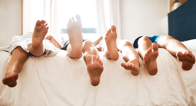 Podnoszenie stóp po całym dniu zabawy. Zbliżenie dzieci leżących boso na łóżku w domu
