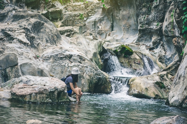 Podróż kobieta siedzi i cieszyć się chwilą na skale w wodospad w parku przyrody