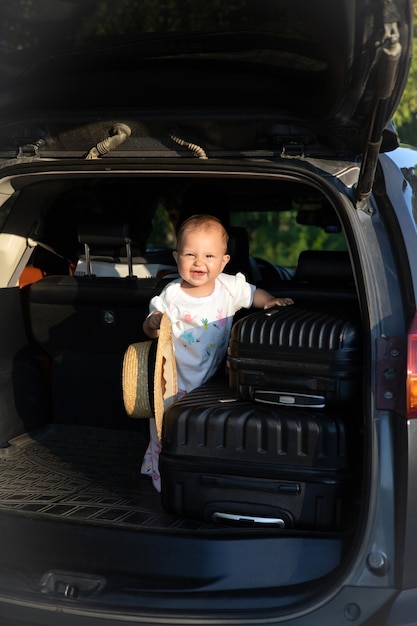 Podróż samochodem z dzieckiem Otwarty bagażnik samochodu Walizki na drodze Dziecko w czapce podróżnika
