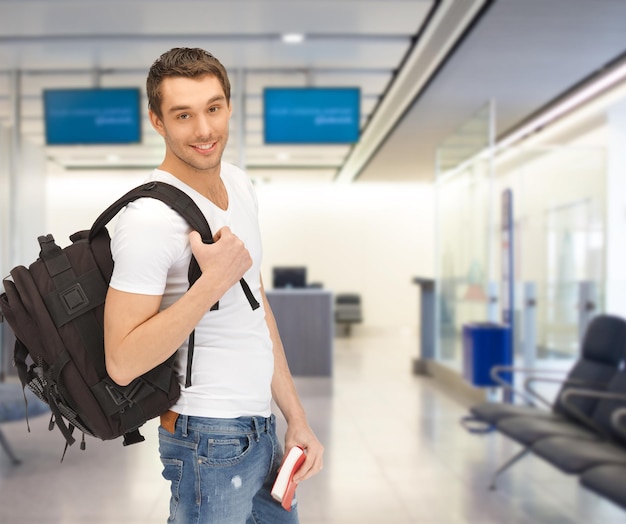 podróże, edukacja, turystyka i ludzie - uśmiechnięta studentka z plecakiem i książką na lotnisku