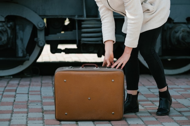 Zdjęcie podróże wycieczka turystyczna wypoczynek. styl życia podróżnika. miejsce na wakacje na stacji kolejowej. kobieta trzymająca walizkę