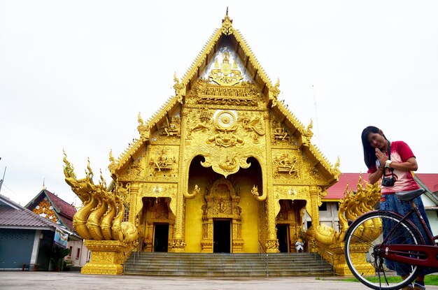 Podróżniczka tajska kobieta podróżuje i modli się przed złotym ubosot lub złotym kościołem w Wat Sri Pan Ton to starożytna świątynia, w której ludzie odwiedzają i modlą się w Nan w Tajlandii