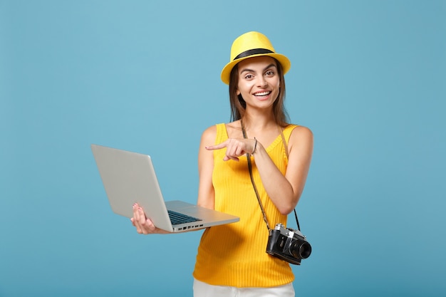 Podróżniczka turystyczna kobieta w żółtych letnich ubraniach, kapeluszu z laptopem na niebiesko
