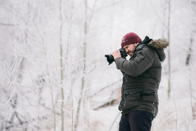 Podróżnik fotograf robi zdjęcia w zimowym lesie