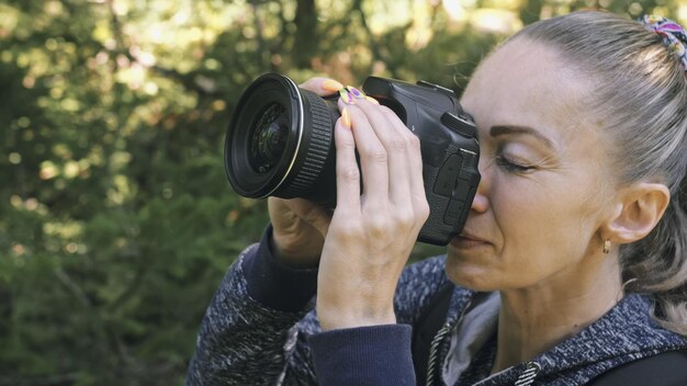 Zdjęcie podróżnik fotografujący malowniczy widok w lesie dziewczyna robi zdjęcie wideo aparatem bezlusterkowym dslr