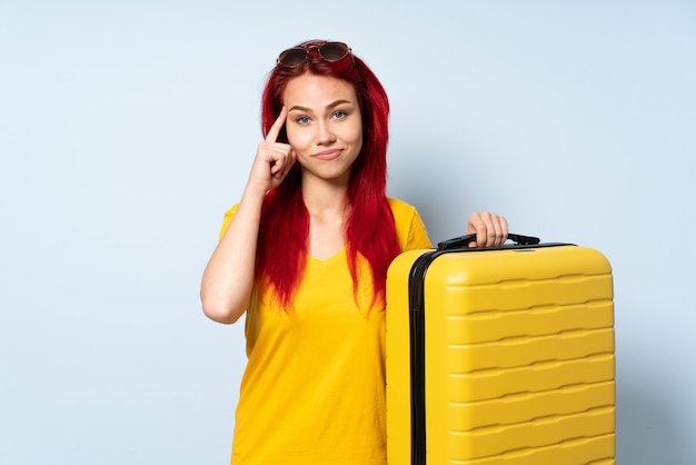Podróżnik kobieta trzyma walizkę odizolowywająca na błękit ścianie myśleć pomysł