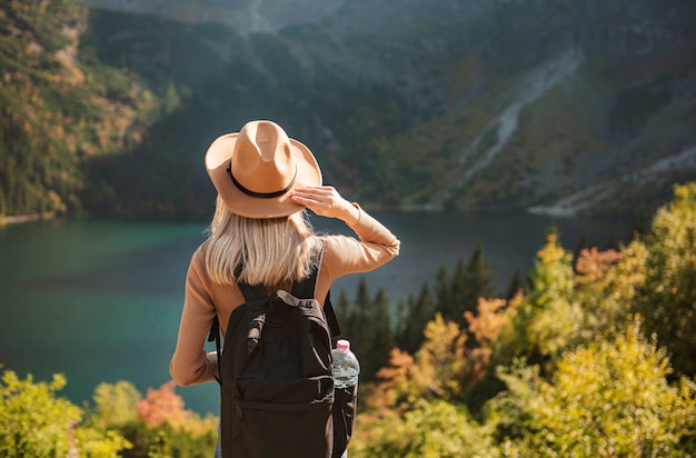 Podróżnik kobieta w kapeluszu i patrząc na niesamowite góry i jezioro, koncepcja podróży wanderlust. Lake Morskoy Eye w polskich Tatrach.