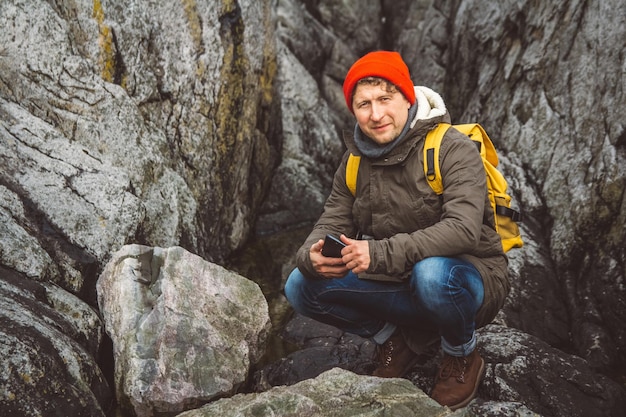 Podróżnik trzymający smartfon w rękach na tle gór i skał
