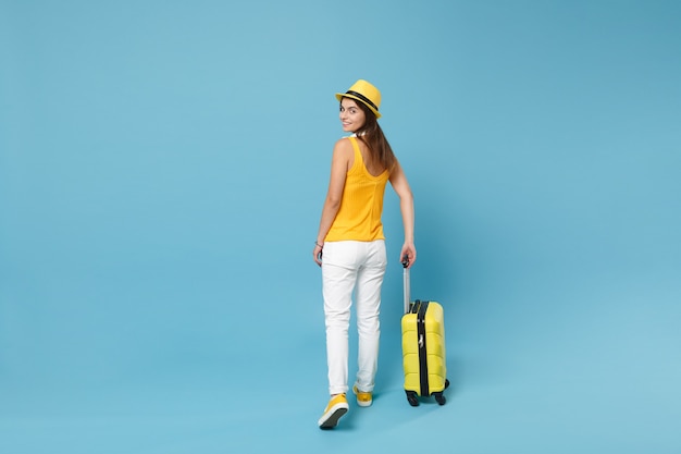 Podróżnik turysta kobieta w żółtych ubraniach casual, kapelusz z walizkowym aparatem fotograficznym na niebiesko