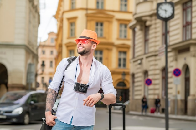 Podróżnik turysta w przypadkowym ubraniu kapeluszu z walizką mężczyzna z bagażem gotowym do podróży na godz