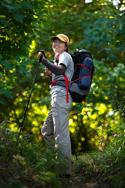 Podróżnik Z Plecakiem I Kijami Trekkingowymi. Kobieta Turystka W Lesie. Podróżnik Kobieta Patrząc Prosto I Uśmiechając Się. Sfotografowany W Rosji.