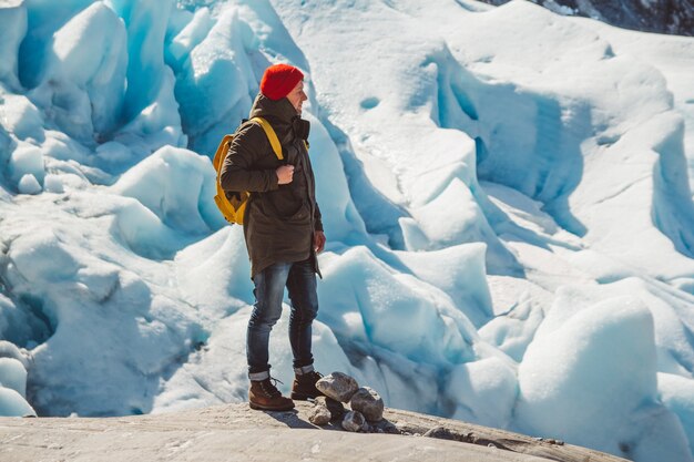 Podróżnik z plecakiem stojący na skale na tle lodowca góry i śnieg