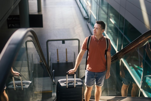 Podróżny idący przez terminal lotniska z walizką stojącą na schodach