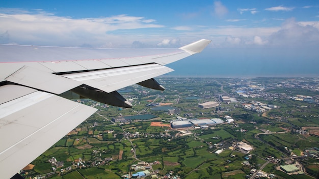 Podróżowanie samolotem. Widok z lotu ptaka miasta na wyspie Tajwan. Zobacz skrzydło samolotu i miasto Taoyuan w tle widziane przez okno samolotu podczas lotu.