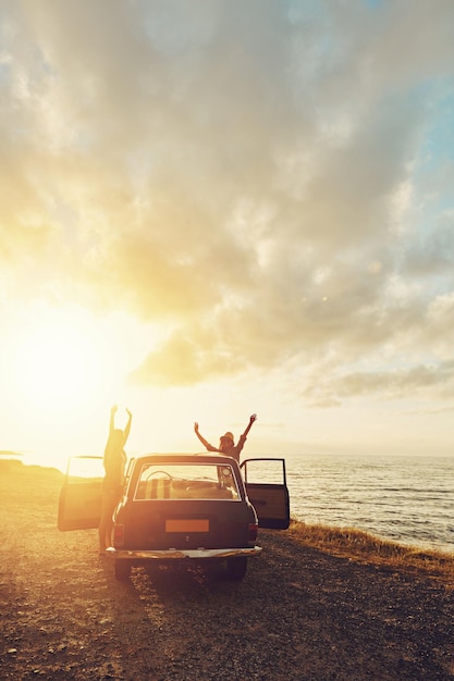 Podróżuj samochodem i parą przyjaciół podczas podróży o zachodzie słońca i wolności na letnie wakacje Świętuj kobiety w stylu vintage i retro z transportem na parking przygodowy i ocean