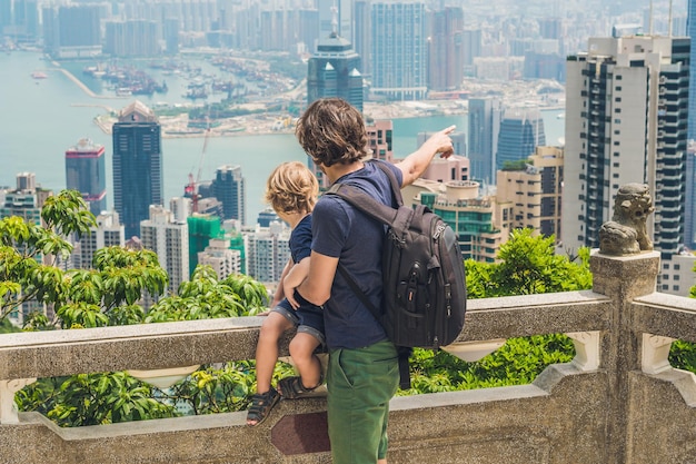 Zdjęcie podróżujący ojciec i syn na szczycie wiktorii na tle hongkongu. podróżowanie z koncepcją dzieci