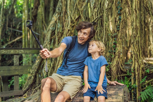 Zdjęcie podróżujący z ojcem i synem odkrywają las ubud w małpim lesie, bali, indonezja. podróżowanie z pojęciem dzieci. wideoblog, selfie...