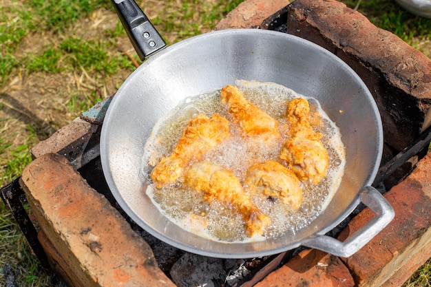 Podudzie z kurczaka w cieście jest smażone na oleju w woku na wsi Gotowanie pysznego jedzenia na pikniku