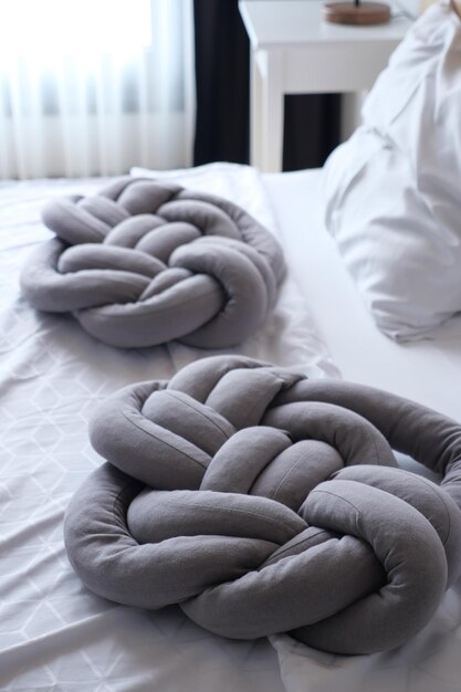 Poduszka koloru szarego na białym łóżku