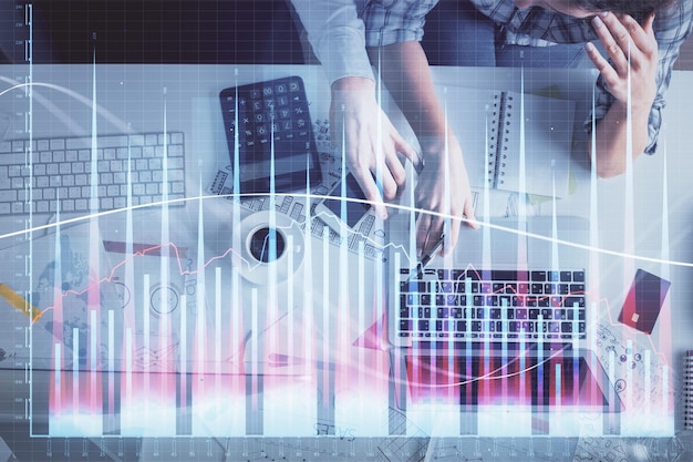 Podwójna ekspozycja mężczyzny i kobiety pracujących razem i wykres finansowy hologram rysunek koncepcja analizy rynku Tło komputera Widok z góry