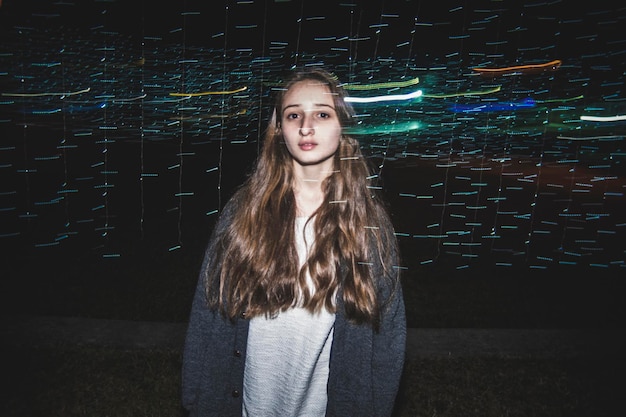Zdjęcie podwójna ekspozycja śladów światła i nastolatka na polu w nocy