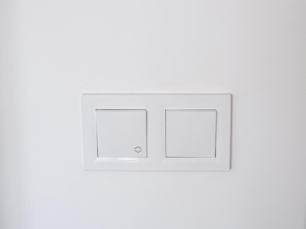 Podwójne białe plastikowe przełączniki mechaniczne zainstalowane na białej ścianie